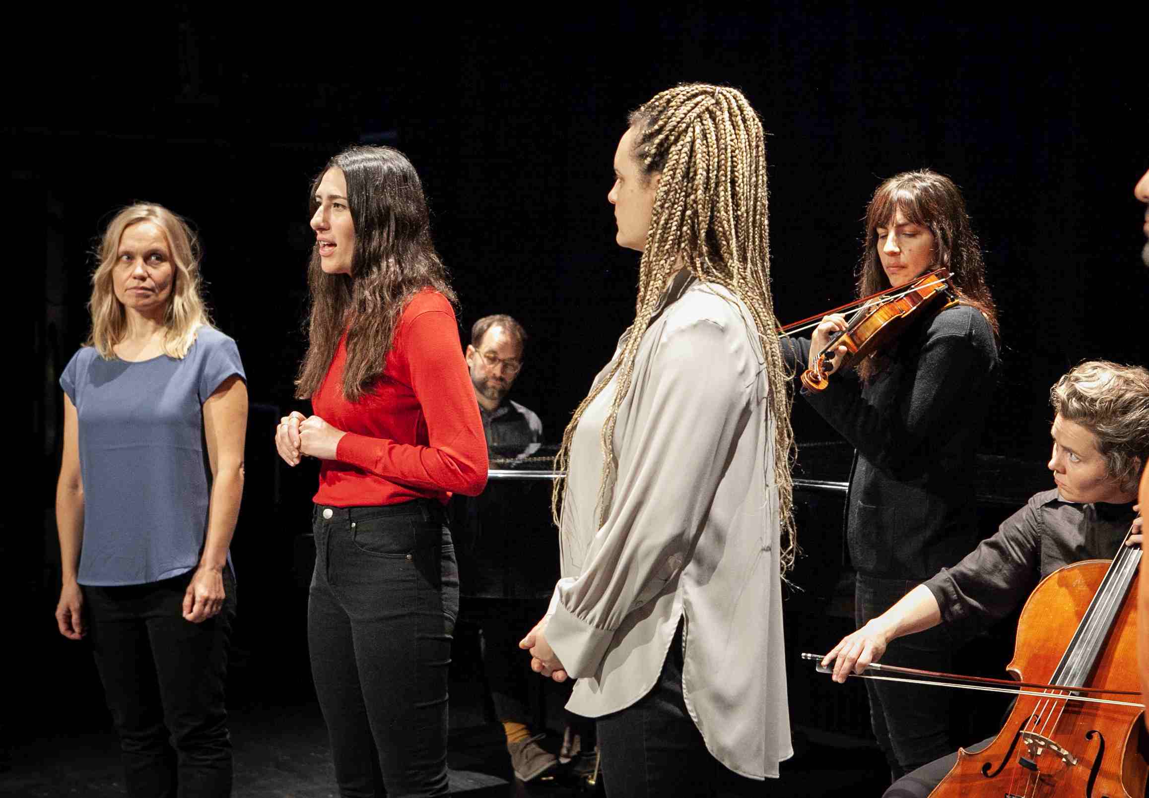 Junge Menschen stehen auf einer Bühne, teils mit Musikinstrumenten.