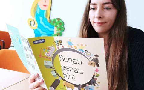 Eine junge Frau schaut sich den Flyer zu "Schau genau hin! Kinderarbeit und Nachhaltigkeit"