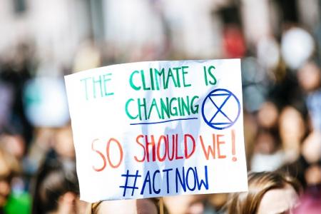 Schild auf Klimademonstration mit der Aufschrift "Climate is changing - so should we act now". Foto von Markus Spiske auf Unsplash