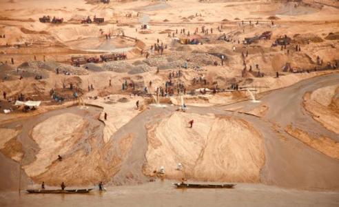 Fotografie von Sandabbau. Aus weiter Höhe fotografiert sieht man Arbeiter*innen und Fahrzeuge in einem Abbaugebiet. Quelle: unsplash, Hasin Hayder