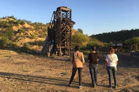 Eine Gruppe Menschen steht vor einem Bohrturm.