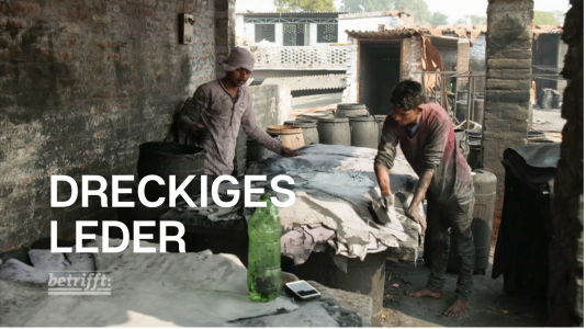 Zwei Arbeiter, die in einem Gerbereibetrieb in Indien ohne Schutzkleidung Leder färben. 