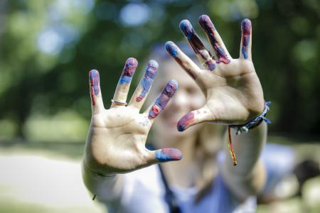 Bunt angemalte Handinnenflächen werden in die Kamera gereckt.