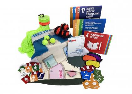Unter anderem bunte Karten mit den SDG-s, Tennisbälle. Die Materialkiste "17 Ziele – Wir für eine bessere Welt – Materialen zum Methodenhandbuch". Bildquelle: Projekt "Eine Welt in der Schule" des Grundschulverbandes e.V.