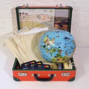 Zu sehen ist ein geöffneter Koffer mit Workshopmaterialien, z. B. ein aufblasbarer Globus, Bilder von Folgen des Klimawandel, Spielbretter, Stoffsäckchen, Stifte. Der Materialkoffer gehört zum Projekttag "Auf der Flucht vor dem Klima".