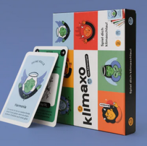 Das Bild zeigt das Kartenspiel klimaxo mit bunter Verpackung in Grün, Rot, Weiß und Orange. Darauf sind gezeichnete Figuren mit verschiedenen Gesichtsausdrücken zu sehen, die symbolisch für Klimatypen stehen. Zwei Spielkarten sind hervorgezogen, eine zeigt den Charakter „Harmonia“.