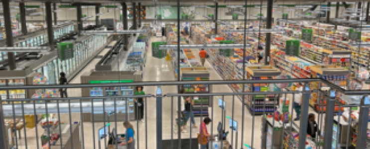 Blick in einen Supermarkt von oben mit Regalen und Menschen.