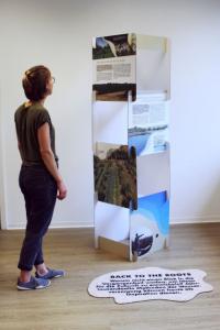 Eine Person in dunkler Kleidung steht vor einer Säule der Ausstellung "Wasserwandel" und liest die Texte.