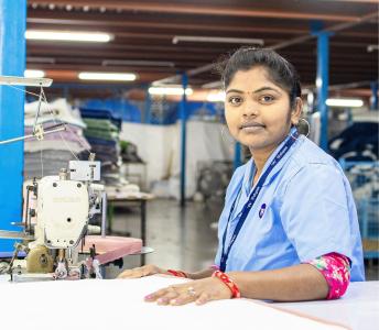 Textilarbeiterin an Nähmaschine in indischer Fabrik 