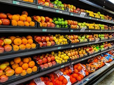 Regale voller frischer Orangen, Äpfel, Zitronen und Limetten im Supermarkt.