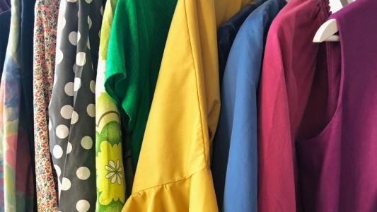 Inneres eines Kleiderschrankes, bunte Kleidung hängt auf Kleiderbügeln.