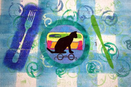 Picknickdecke mit Gabel, Messer und Teller mit einer Schwarzen Katze