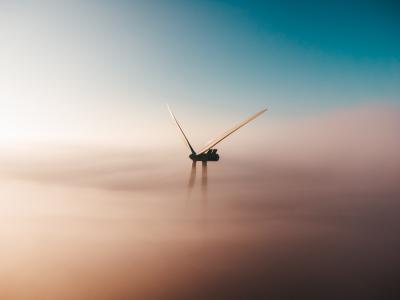 Titelbild "Klimaziele und Energiewende". Ein Windrad im Nebel. Quelle: unsplash.com/@sanderweeteling