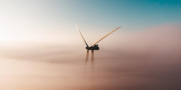 Titelbild "Klimaziele und Energiewende". Ein Windrad im Nebel. Quelle: unsplash.com/@sanderweeteling