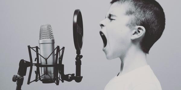 Junge singt am Mikrofon mit Popfilter. Foto von Jason Rosewell auf Unsplash